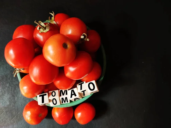 Rote Tomate vegitable geschrieben auf Blöcken in Platte auf schwarzem Hintergrund Platz für Text gehalten — Stockfoto