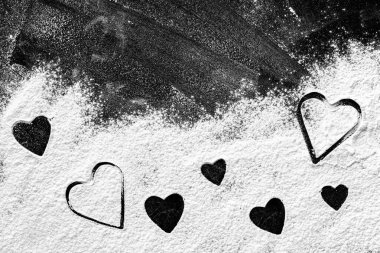 Koyu tahta ya da masa üzerinde undan yapılmış kalp şekilleri, üst görünüm. Mesaj için yer var. Sevgililer Günü ve aşk konsepti. Sevgiyle ev yapımı yemek. Sevgililer Günü için özel menü ve yemek.