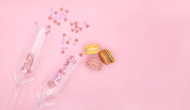 İçinde küçük kalpler olan iki şampanya bardağı ve pembe arka planda mesajlaşmak için yeri olan kurabiyeler. Vanetines Günü, aşk konsepti. Tatlı yemek, tatlı masa, menü.