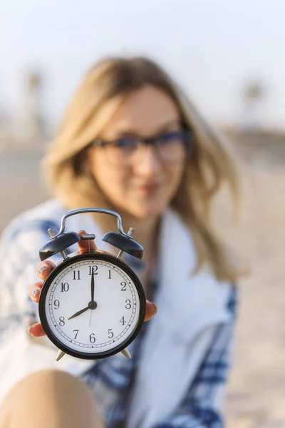 Selective Focus on the clock. Clock on the morning beach, blurred young business woman on background. Freelance, time management concept. Stress at Work