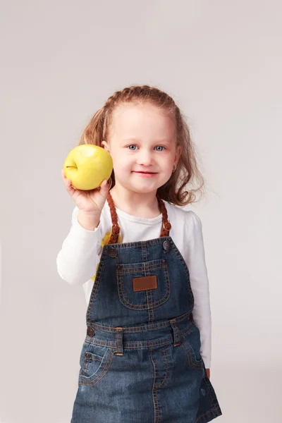 Pretty little girl holding apple in studio — Stock Photo, Image