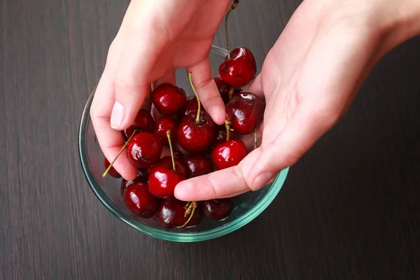 Fresh cherries in hands on table — Stock Photo, Image