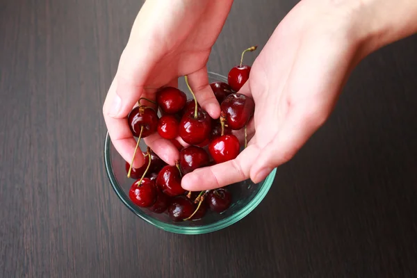 Fresh cherries in hands on table — Stock Photo, Image