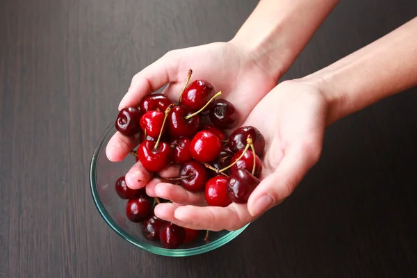 Fresh cherries in hands on table — Stock Photo, Image