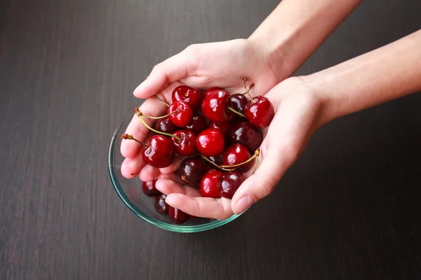 Fresh cherries in hands on table — Stock Photo, Image