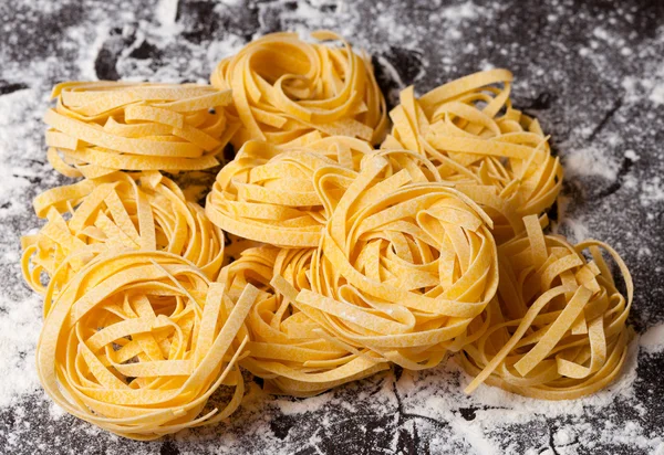 Tagliatelle de pasta cruda en la mesa —  Fotos de Stock