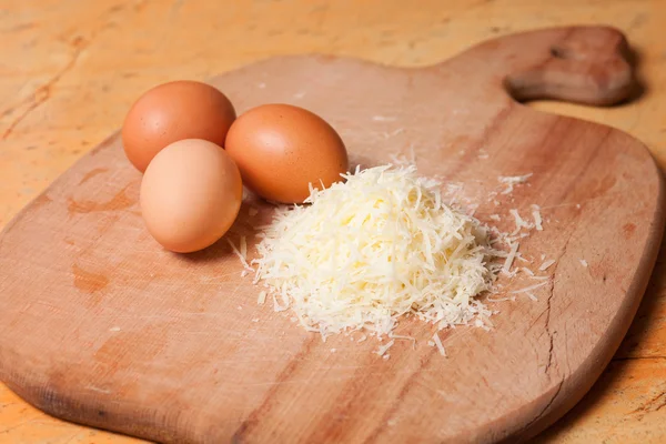 Grated parmesan and eggs on table — Stock Photo, Image