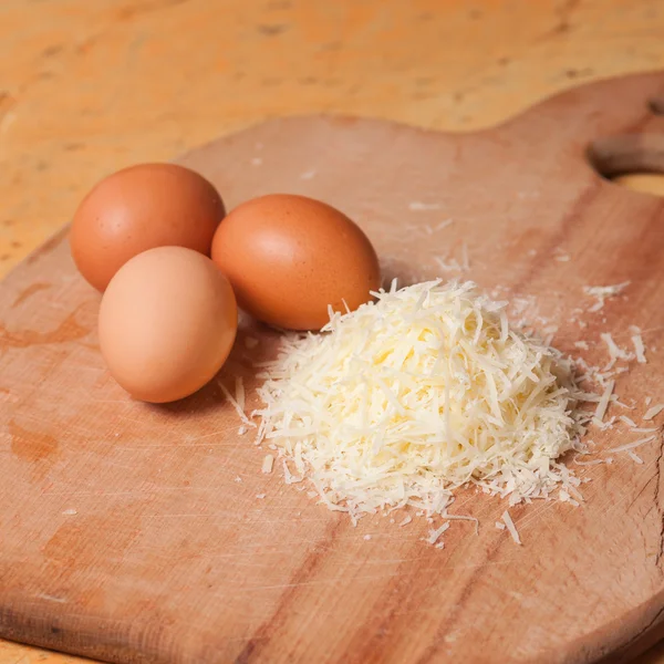 Grated parmesan and eggs on table — Stock Photo, Image