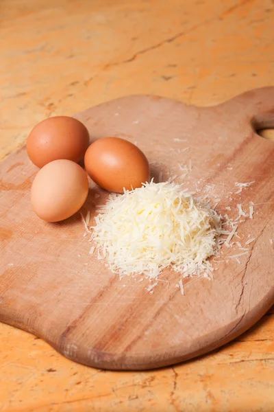 Grated parmesan and eggs on table — Stock Photo, Image