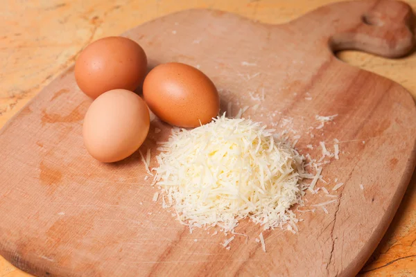 Grated parmesan and eggs on table — Stock Photo, Image