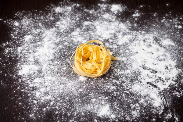 Tagliatelle de pasta cruda en la mesa —  Fotos de Stock