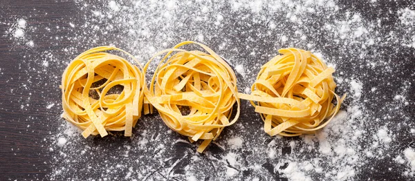 Macarrão cru tagliatelle na mesa — Fotografia de Stock