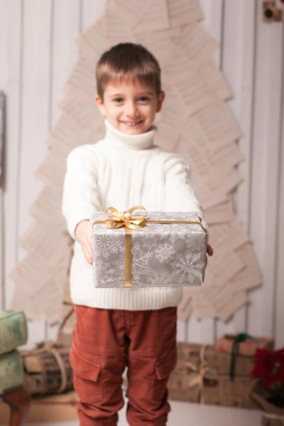 Kleiner Junge hält Geschenk im weihnachtlichen Interieur — Stockfoto