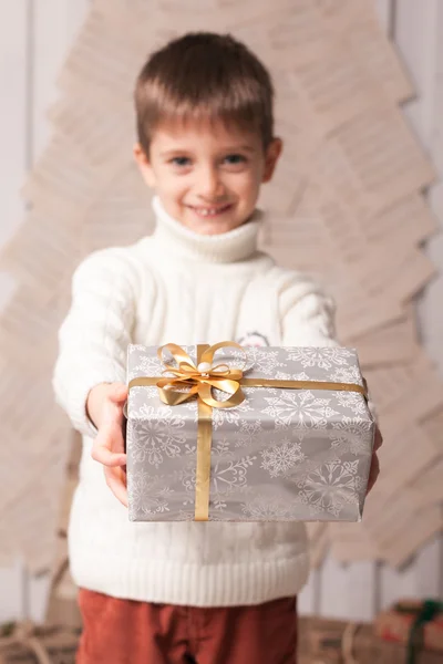 Kleiner Junge hält Geschenk im weihnachtlichen Interieur — Stockfoto