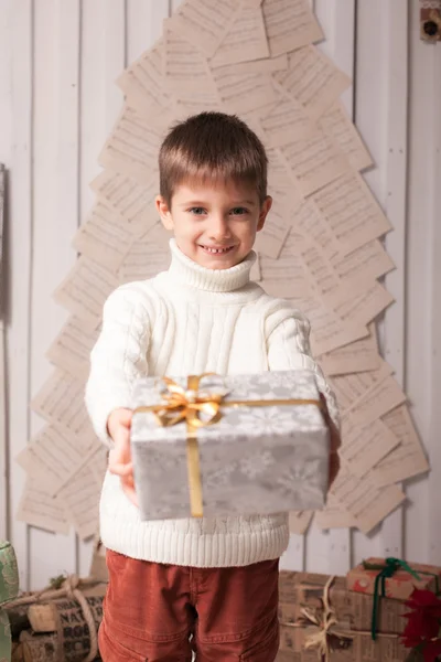 Kleiner Junge hält Geschenk im weihnachtlichen Interieur — Stockfoto