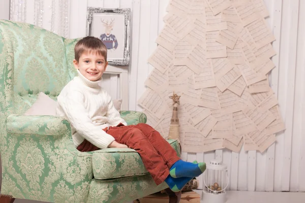 Little smiling boy on chair in Christmas interior — Stock Photo, Image