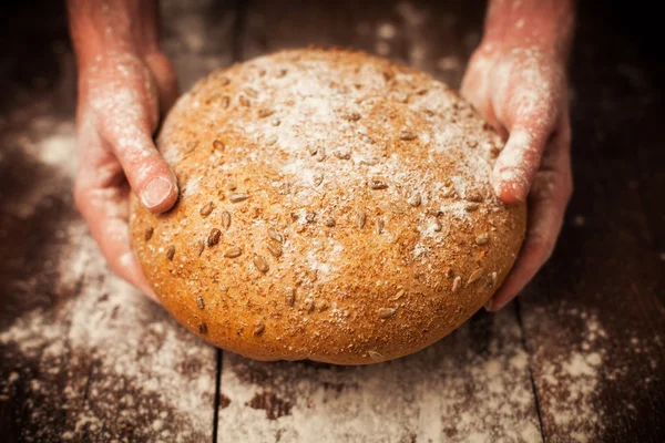 Baker mãos com pão fresco na mesa — Fotografia de Stock