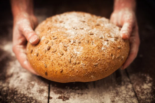 Baker mãos com pão fresco na mesa — Fotografia de Stock