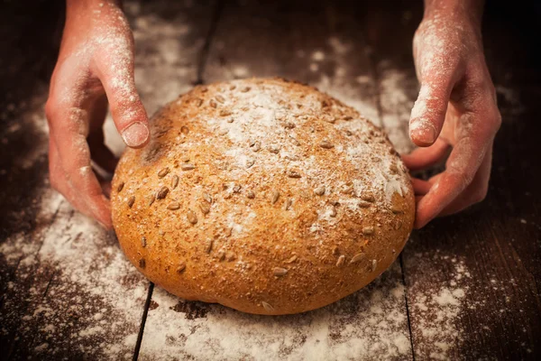 Mani di fornaio con pane fresco sul tavolo — Foto Stock