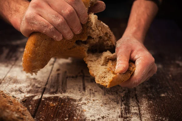 Baker ruce s čerstvý chléb na stůl — Stock fotografie