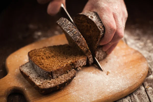 Mani maschili affettare pane fresco sul tavolo — Foto Stock