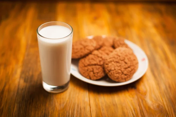 Galletas de avena y vaso de leche en la servilleta sobre la mesa —  Fotos de Stock