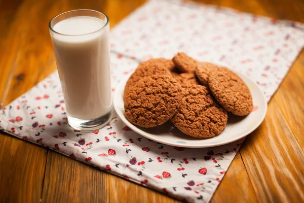 Haferflockenkekse und ein Glas Milch auf Serviette auf dem Tisch — Stockfoto