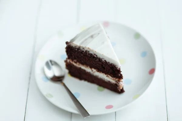 Bolo de chocolate em placa branca na mesa de madeira — Fotografia de Stock