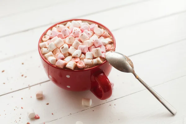 Chocolate caliente con malvaviscos en taza roja en la mesa — Foto de Stock