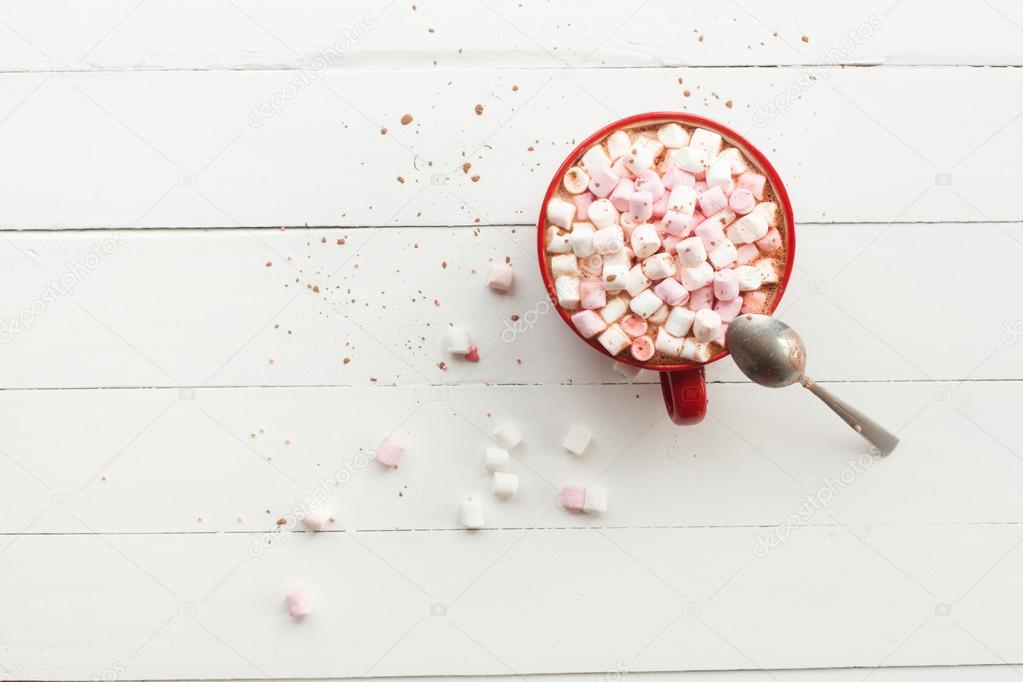 Hot chocolate with marshmallows in red cup on table