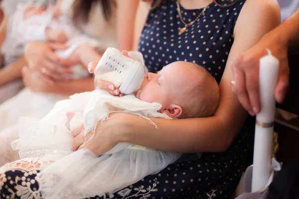 Маленькая девочка на руках у матери, церемония крещения — стоковое фото