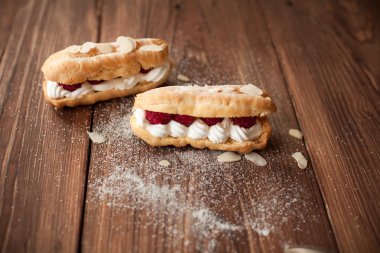 Ahşap masa üzerinde taze ahududu ile krem eklerleri