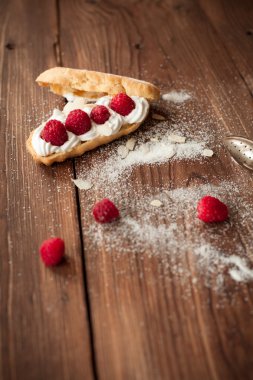 Ahşap masa üzerinde taze ahududu ile krem pasta