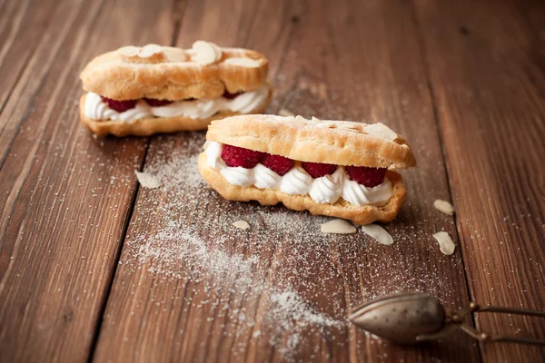 Pasteles de crema con frambuesas frescas en la mesa de madera — Foto de Stock