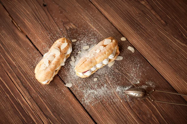 Crème eclairs met verse frambozen op houten tafel — Stockfoto