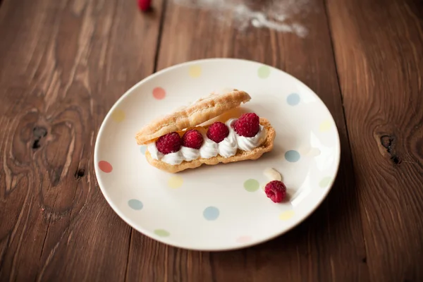 木製テーブルの上皿に新鮮なラズベリーとクリームのデザート — ストック写真