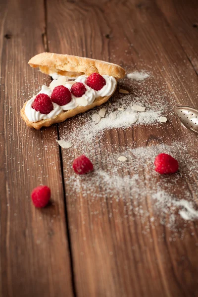 Ahşap masa üzerinde taze ahududu ile krem pasta