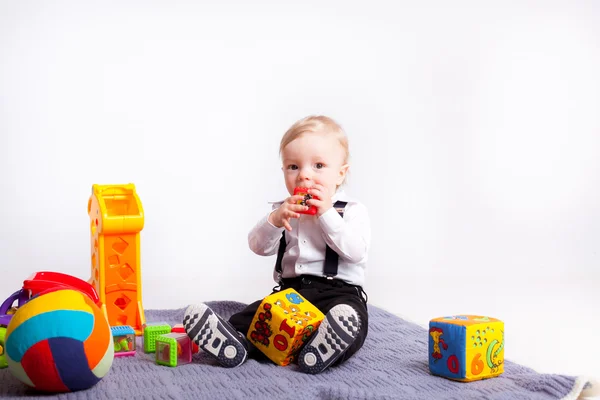 Маленький мальчик играет с игрушками на одеяле на белом фоне — стоковое фото