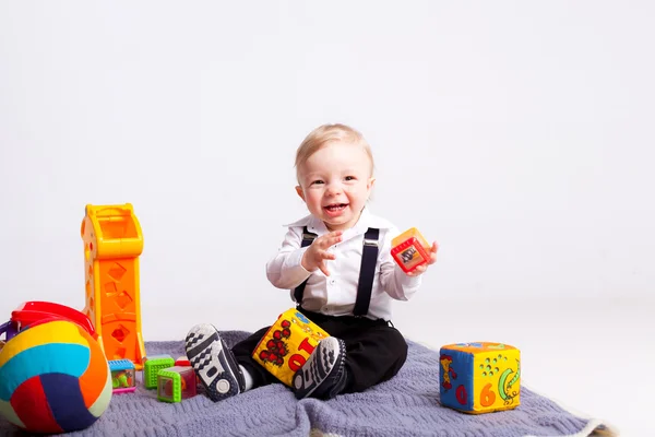 Счастливый мальчик на одеяле с игрушками на белом фоне — стоковое фото