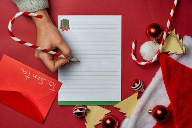 Beyaz çarşafa, kırmızı zarfa, santaclaus şapkasına, ağaç şeklindeki ahşap süslemelere ve şeker kamışlı kırmızı ve beyaz noel toplarına yılbaşı kalemi koymak için kırmızı Noel arkaplanı.