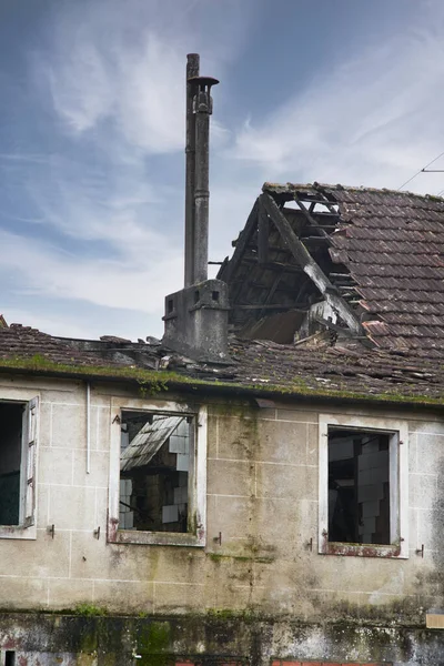 Abandoned stone house with broken wooden window. old window with wood in an old Galician house with cloudy sky and vegetation around it.