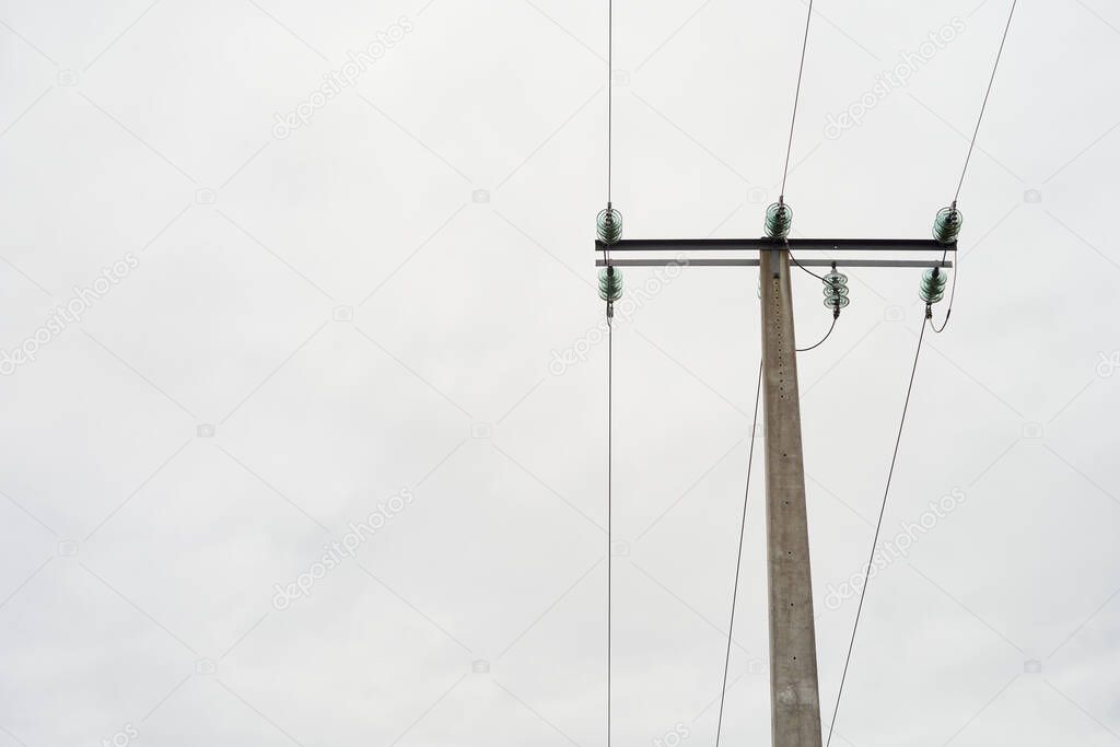 electric tower with cloudy sky in the background and high voltage cables, gray stone tower with metallic electrical cables.