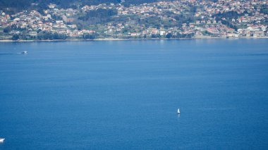 Tekne Vigo nehrinden geçiyor ve arka planda şehirler var. Vigo şehrinde yelkenli gemi. Mavi Atlantik denizi ve yeşil bitki örtüsü