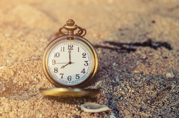 vintage pocket watch on sand beach background