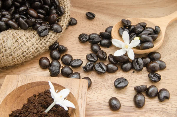Granos de café en saco sobre fondo de madera decoración con pan de maíz y flor —  Fotos de Stock