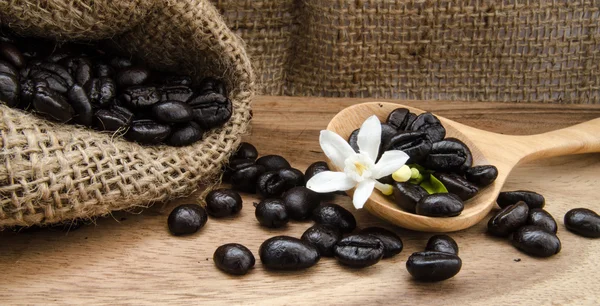 Granos de café en saco sobre fondo de madera decoración con pan de maíz y flor —  Fotos de Stock