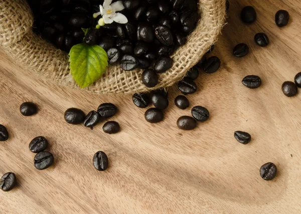 Granos de café en saco sobre fondo de madera decoración con pan de maíz y flor —  Fotos de Stock