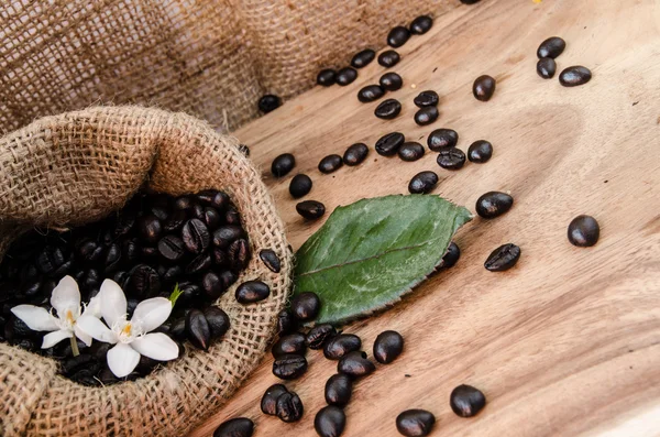 Grano de café en saco sobre fondo de madera .decoration con brean de flores y maíz —  Fotos de Stock