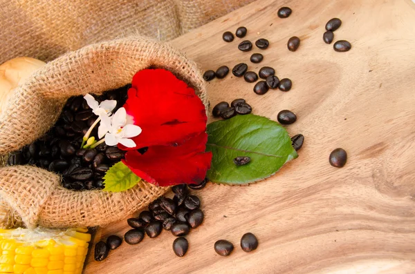 Grano de café en saco sobre fondo de madera .decoration con brean de flores y maíz —  Fotos de Stock