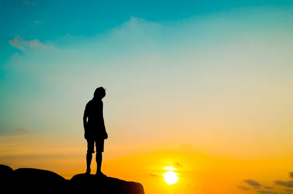 Silhouette homme debout sur pierre et coucher de soleil ciel fond — Photo